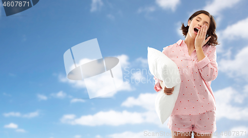 Image of sleepy yawning young woman in pajama with pillow