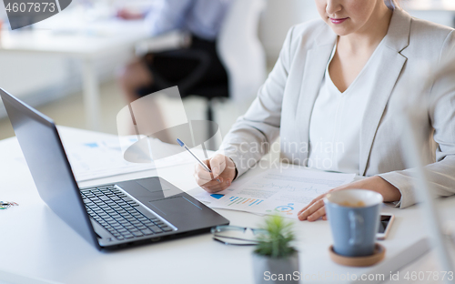 Image of businesswoman with papers working at office