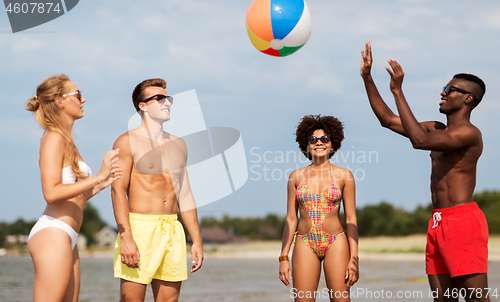 Image of friends playing with beach ball in summer