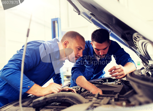 Image of mechanic men with wrench repairing car at workshop