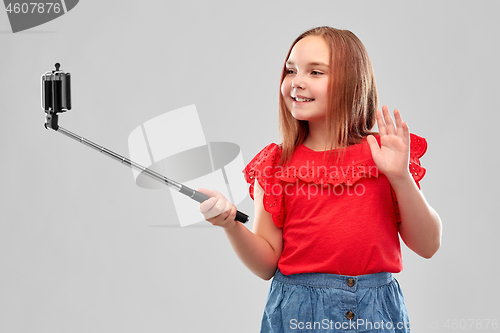 Image of girl taking picture by smartphone on selfie stick