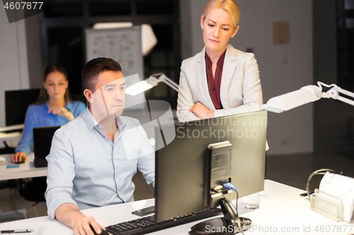 Image of business team with computer working late at office