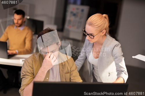 Image of business team with computer working late at office