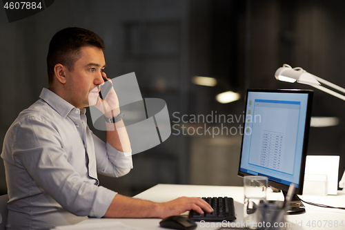 Image of businessman calling on sartphone at night office