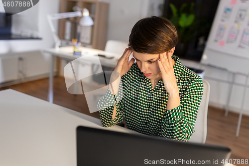 Image of stressed businesswoman at night office