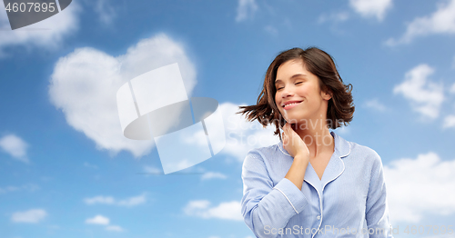 Image of happy young woman in pajama over sky background