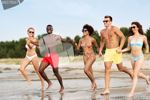 Image of happy friends running on summer beach