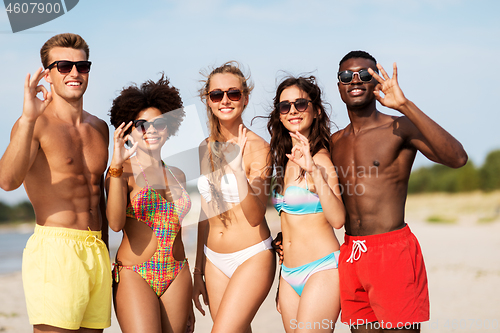 Image of happy friends hugging on summer beach