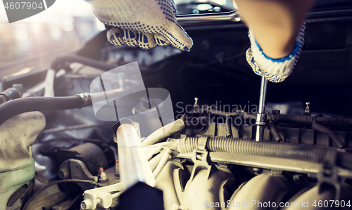 Image of mechanic man with wrench repairing car at workshop