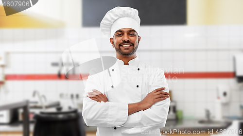 Image of happy indian chef in toque at restaurant kitchen