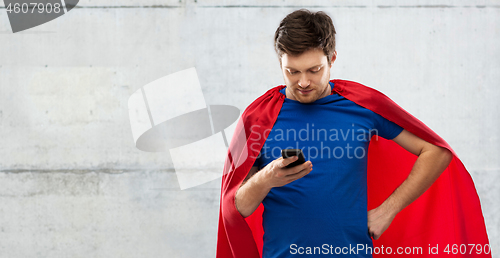 Image of young man in red superhero cape using smartphone