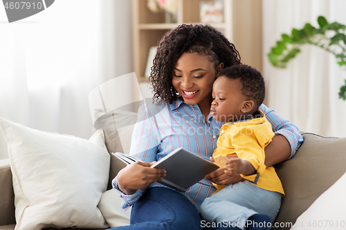 Image of african american mother with book and baby at home