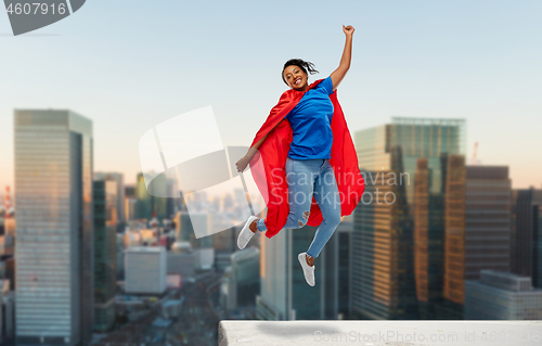 Image of happy african american woman in superhero red cape