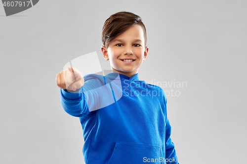 Image of smiling boy in blue hoodier pointing finger