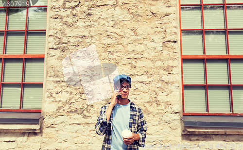 Image of man with smartphone drinking coffee on city street