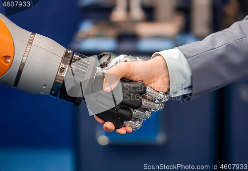 Image of Hand of a businessman shaking hands with a Android robot.