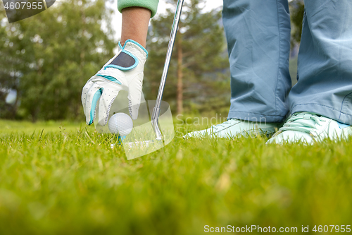 Image of Hand in glove placing golf ball on tee