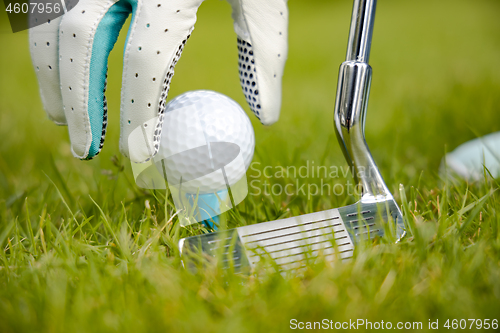 Image of Hand in glove placing golf ball on tee