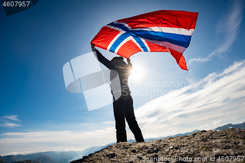 Image of Woman with a waving flag of Norway on the background of nature