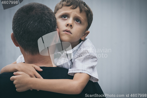 Image of Portrait of young sad little boy and father standing outdoors at