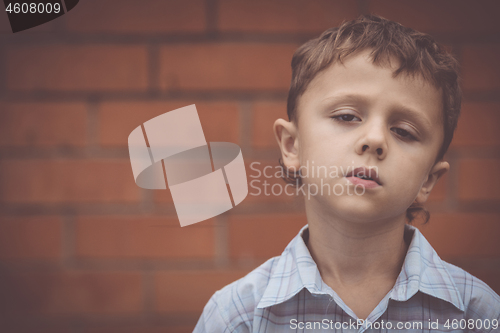 Image of portrait one sad little boy standing near a wall