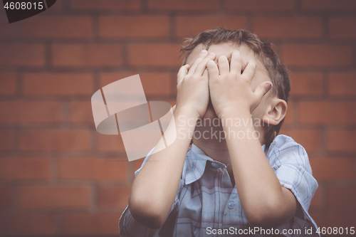 Image of portrait one sad little boy standing near a wall