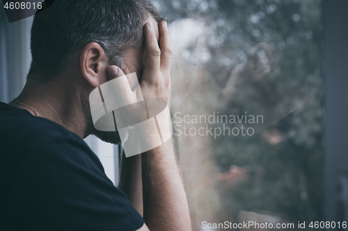 Image of portrait one sad man standing near a window