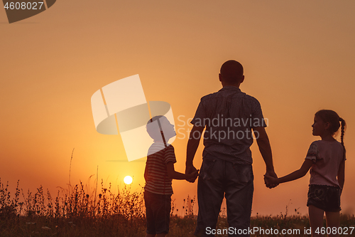 Image of Father and children standing in the park at the sunset time. 