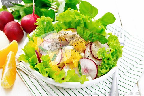 Image of Salad of radish and orange with mint on white wooden board