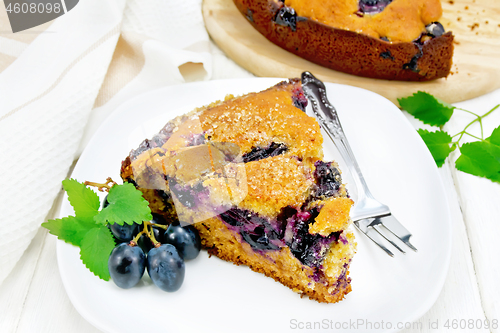 Image of Pie with black grapes  in plate on white board