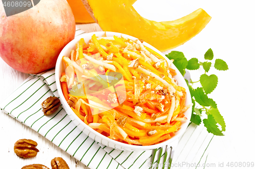 Image of Salad of pumpkin and apple with nuts in bowl on white board