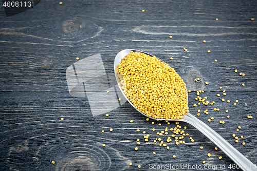 Image of Mustard seeds in metal spoon on board