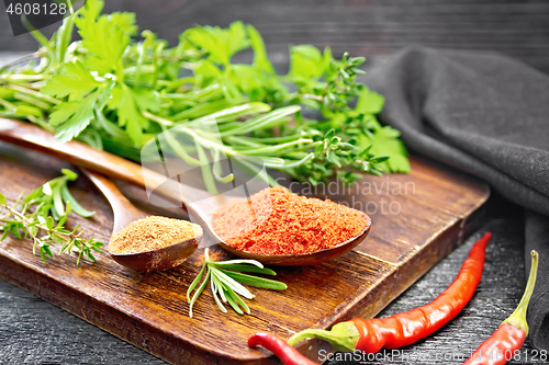 Image of Peppers red and paprika powder in spoon on black board