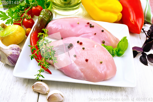 Image of Chicken breast raw in plate with vegetables on light board