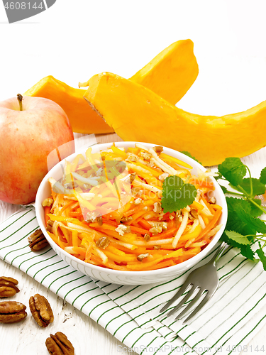 Image of Salad of pumpkin and apple with nuts in bowl on board
