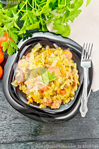 Image of Cabbage stew with sausages in plate on board top