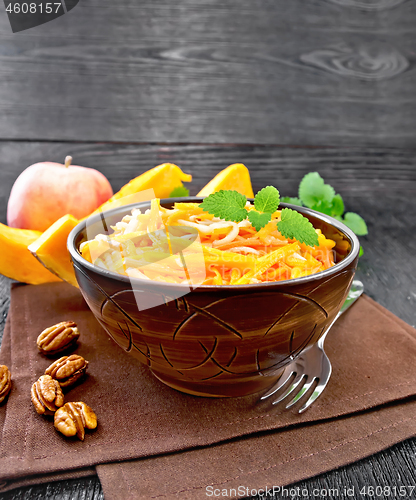 Image of Salad of pumpkin and apple with nuts in bowl on dark board