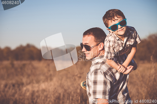 Image of Father and son playing on the field at the day time.