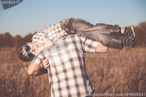 Image of Father and son playing on the field at the day time.