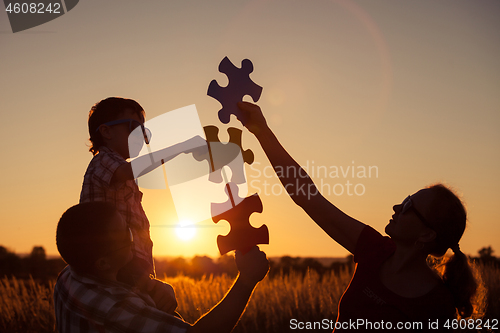 Image of Happy family playing at the park at the sunset time. 