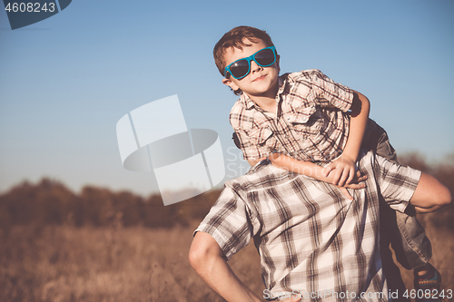 Image of Father and son playing on the field at the day time.