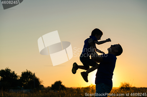 Image of Father and son playing in the park at the sunset time.