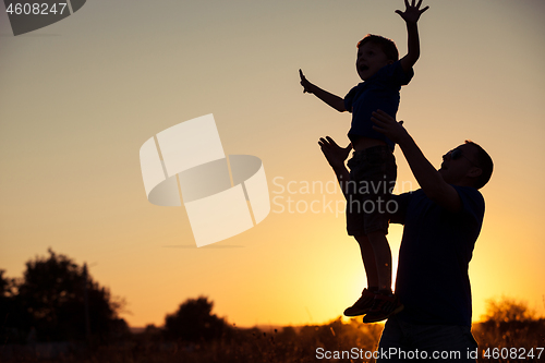 Image of Father and son playing in the park at the sunset time.