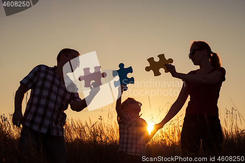 Image of Happy family playing at the park at the sunset time.