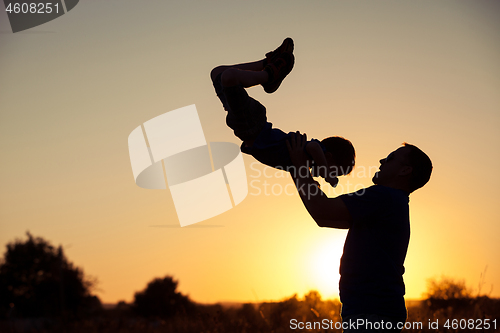 Image of Father and son playing in the park at the sunset time.