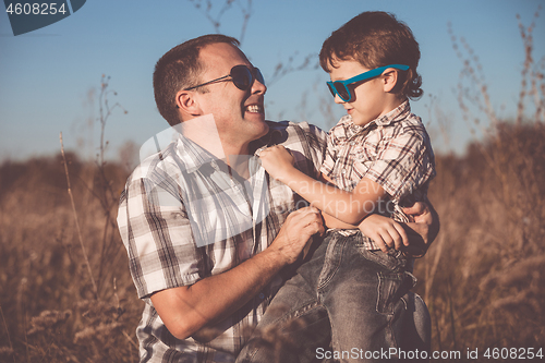 Image of Father and son playing on the field at the day time.