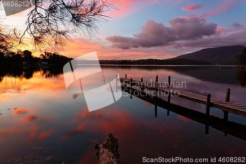 Image of Scenic sunset and reflections on lake with old jetty 