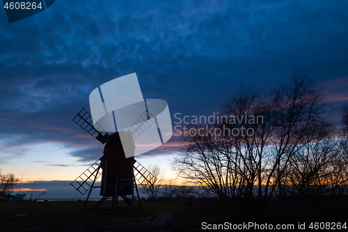 Image of Old windmill silhouette by a cloudy sky