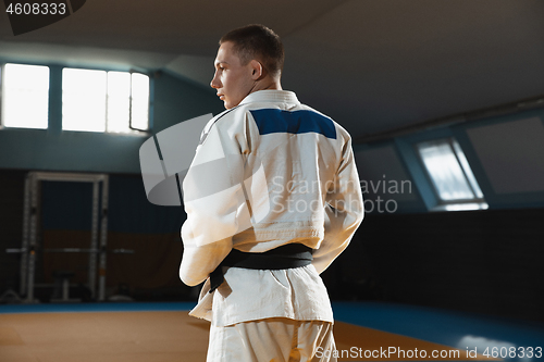 Image of Young judo fighter in kimono posing comfident in the gym, strong and healthy