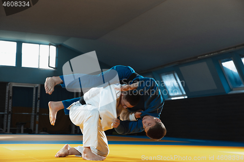 Image of Two young judo fighters in kimono training martial arts in the gym with expression, in action and motion